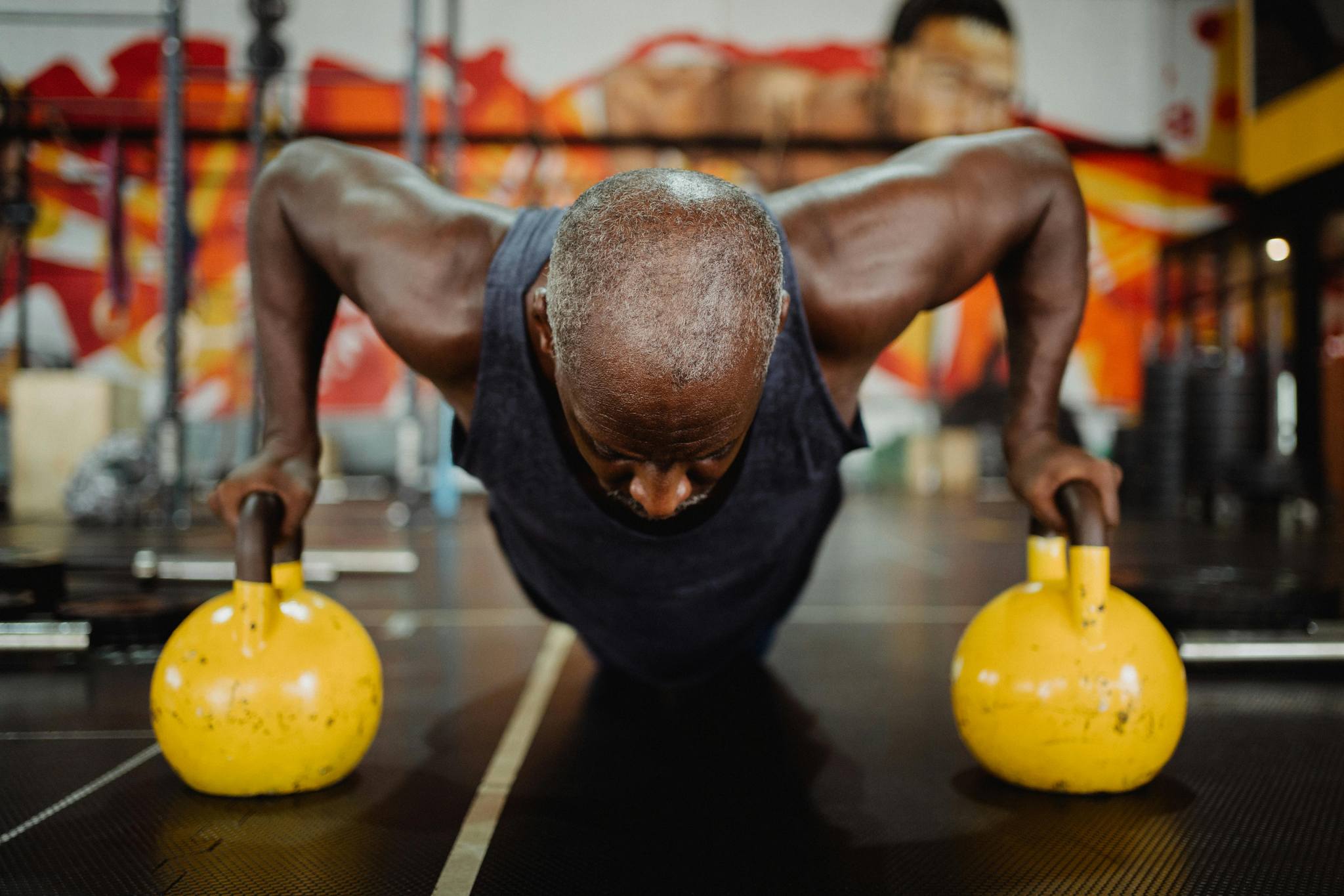 "A man at a gym doing push-ups with kettle bells, symbolizing building strength and resilience in addiction recovery.